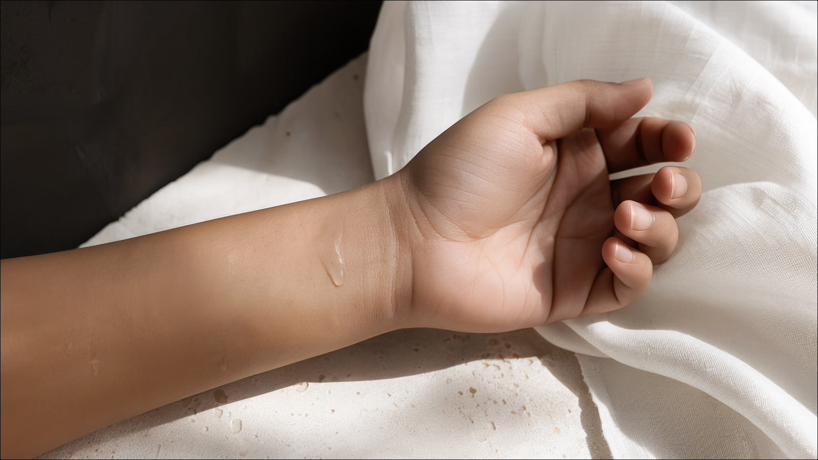 Bare hands holding a trace of clear oil in warm daylight.