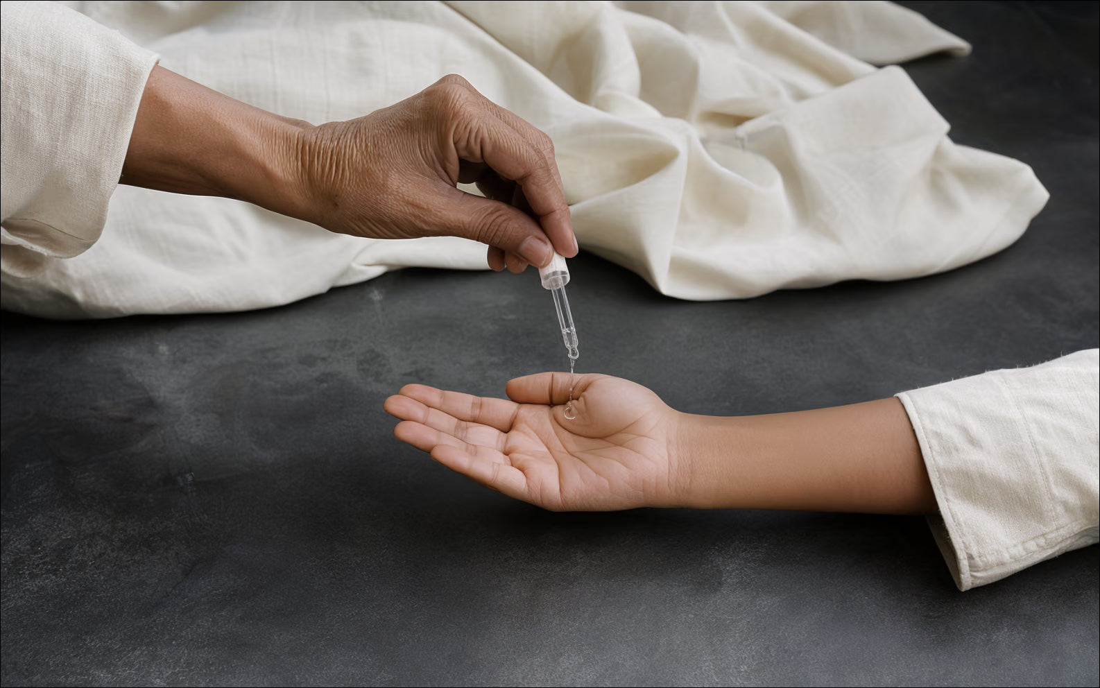An older South Asian hand passes a clear-oil gesture to a younger open palm.