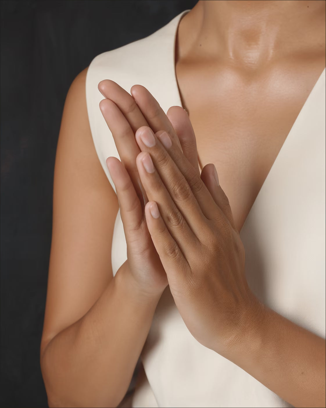 Hands warming a small amount of clear face oil between the palms.